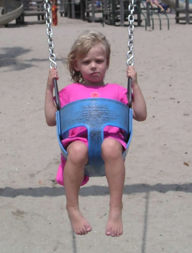 Lauren Had as a young child seated in a playground swing. She squints in the sun, her bare feet dangling, as she stares defiantly at the camera.